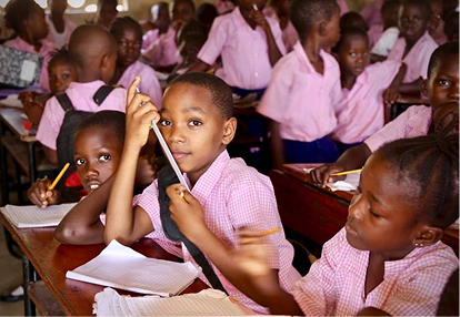 Enfants en classe scolaire écrivant dans des cahiers assis à des bureaux